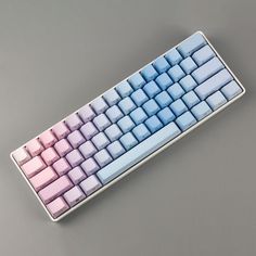 a pink and blue keyboard sitting on top of a gray table next to a black mouse