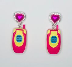 pair of pink and yellow earrings with heart shaped earring clippings on white background