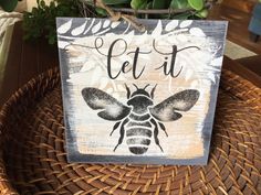 a wooden sign that says let it bee with a black and white design on it