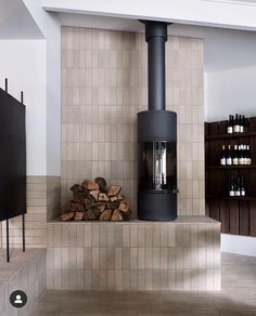 a wood burning stove sitting inside of a living room next to a pile of logs