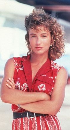 a woman with her arms crossed standing in front of an airplane