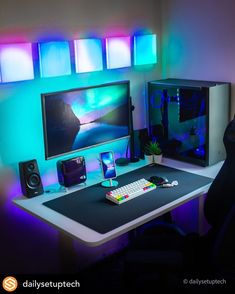 a desk with a computer monitor, keyboard and phone on it in front of some colorful lights