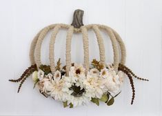 a white pumpkin decorated with flowers hanging on a wall