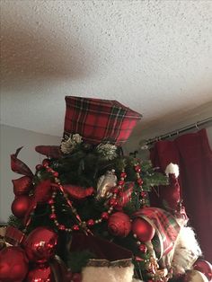 a christmas tree decorated with red and green ornaments, plaid hats, and other holiday decorations