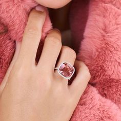 a woman's hand with a ring on her finger and a pink fur coat