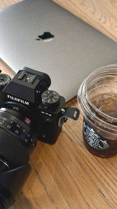 a laptop computer sitting on top of a wooden table next to a cup of coffee