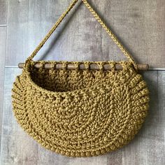 a crocheted purse hanging on a wall with a wooden handle and string attached to it