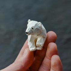 a hand holding a small white polar bear ornament