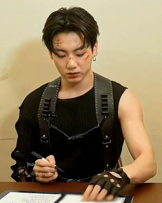 a young man in black shirt sitting at table with cell phone and laptop on it