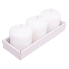 three white candles in a box on a white background