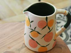 a ceramic pitcher with oranges painted on it