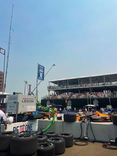 some tires are lined up in front of the pit at a race track as people watch