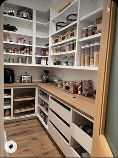 an organized pantry with white shelves and wooden flooring is seen in this image from the inside