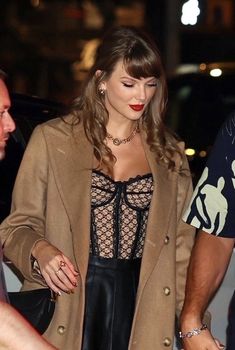 a woman in a black dress and coat walking down the street with a man behind her