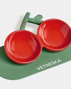 two red bowls sitting on top of a green mat with the words vetreska