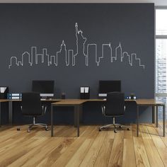 an office area with two desks and a city skyline wall decal on the wall