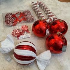 red and white christmas ornaments on a table with candy canes, lollipops and candies