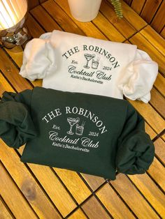 the robinson cocktail club t - shirt laying on a wooden floor next to a candle