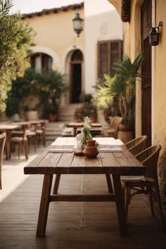 a wooden table sitting on top of a patio covered in potted plants and greenery