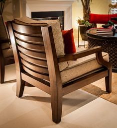 a wooden chair sitting in front of a fire place next to a table with a red pillow on it