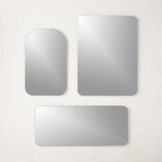 three mirrors are shown on the wall, one is silver and the other is white