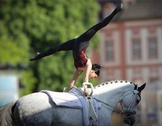 a woman is doing a handstand on the back of a horse while riding it