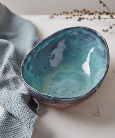 a blue and green bowl sitting on top of a white counter next to a gray towel