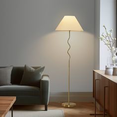 a living room scene with focus on the floor lamp and sofa in the foreground