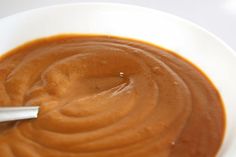 a white bowl filled with brown sauce on top of a table