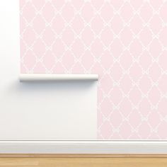 a pink wall with a white pattern on it and a wooden floor in front of it