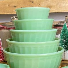 a stack of green bowls sitting on top of a wooden table next to christmas trees