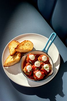 a white plate topped with food next to two pieces of bread on top of a blue table