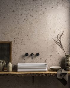 a bathroom sink sitting on top of a wooden counter next to vases and a mirror