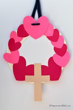 a paper heart wreath with a cross hanging from it