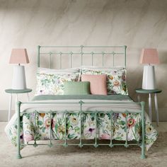 a green metal bed frame with flowers on it and two nightstands next to it