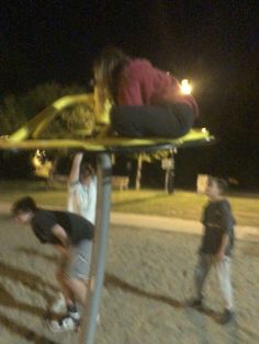 three people are playing with a frisbee in the park at night time,