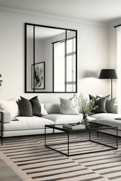 a living room filled with furniture and a large mirror on the wall above it's windows