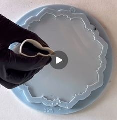 a person in black gloves is using scissors to cut out the top of a plate