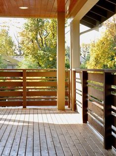 an empty wooden porch with railings and trees in the background