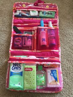 an open pink suitcase on the floor with toiletries and personal care items in it