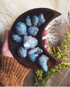 a person holding a wooden bowl filled with blue crystals