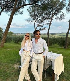 a man and woman standing next to each other in front of a table covered with white cloths