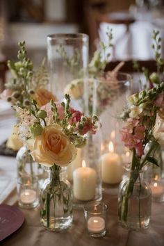 several vases with flowers and candles on a table