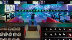 a bowling alley with several lanes full of bowling balls and two rows of seats in front of them