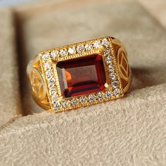 a gold ring with an orange stone surrounded by white and yellow diamonds on top of a box