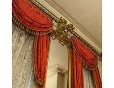 an ornate gold framed mirror with red drapes