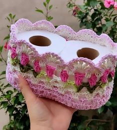 a hand holding a box with two rolls of toilet paper in it and pink flowers on the inside