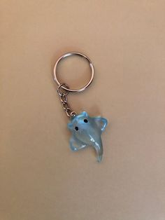 a blue elephant keychain sitting on top of a brown table next to a white wall