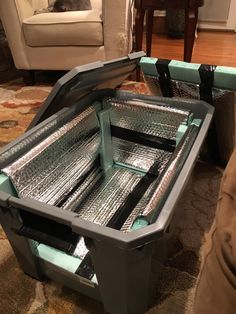 two plastic storage containers sitting on top of a carpeted floor next to a couch