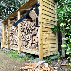 a pile of firewood sitting next to a wooden shed on top of a sidewalk